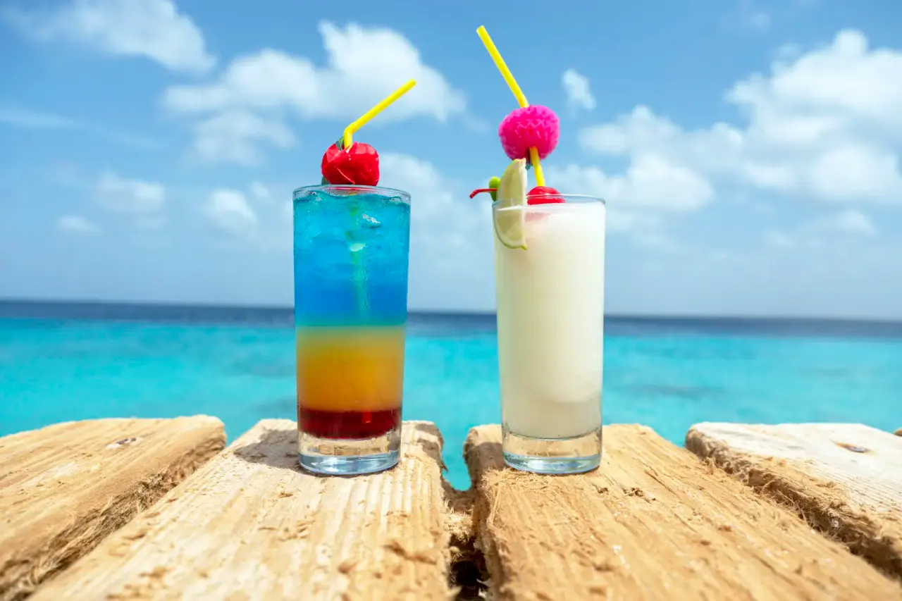 Twee cocktails op een houten steiger met de zee van Bonaire op de achtergrond