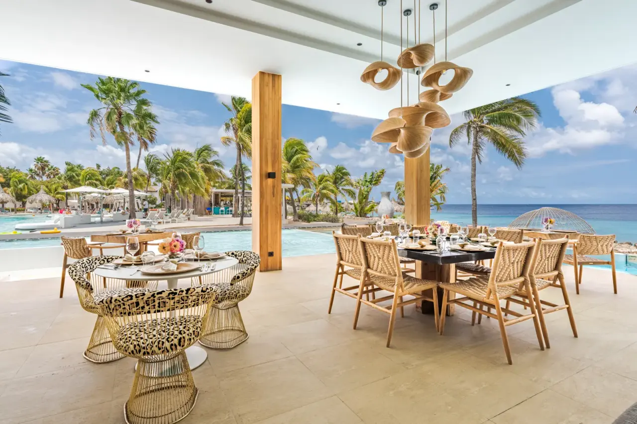 Gedekte tafels op het restaurantterras van Van der Valk Bonaire met zicht op zwembad en zee