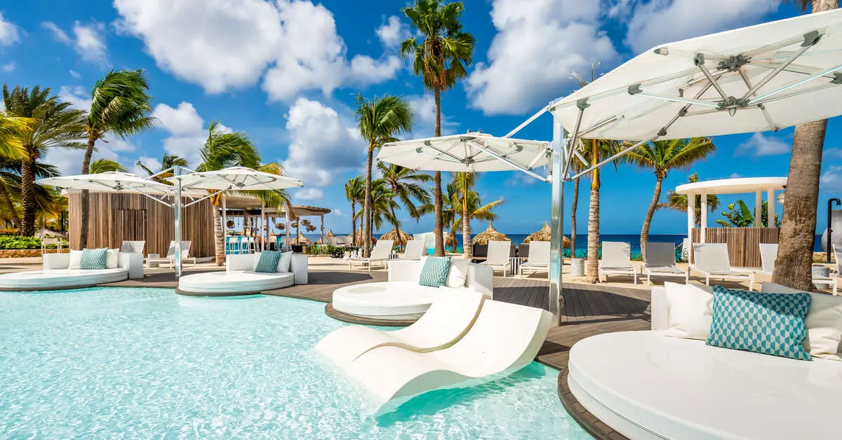 Zwembad van Van der Valk Bonaire met ligbedden in het ondiepe water en witte parasols